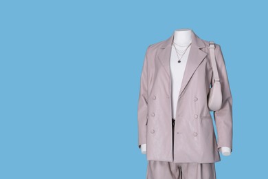 Female mannequin dressed in white t-shirt and stylish leather suit with accessories on light blue background, space for text