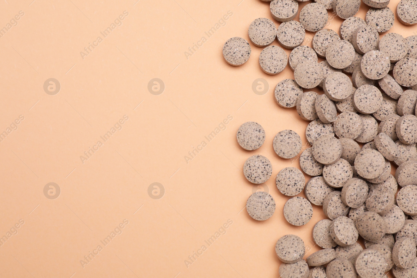 Photo of Beer yeast pills on pale orange background, flat lay. Space for text