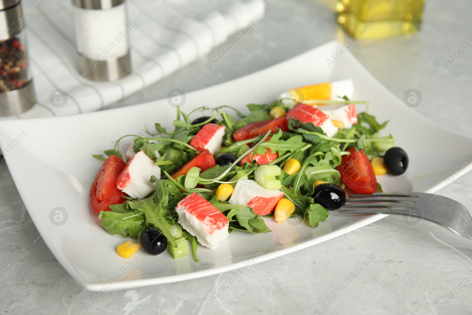 Photo of Tasty crab stick salad served on grey marble table