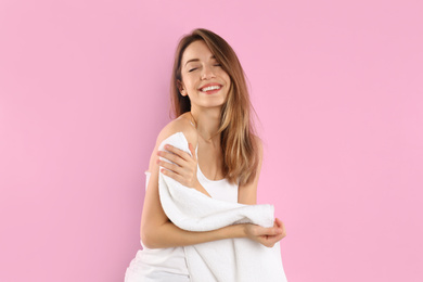 Photo of Young woman wiping body with towel on light pink background