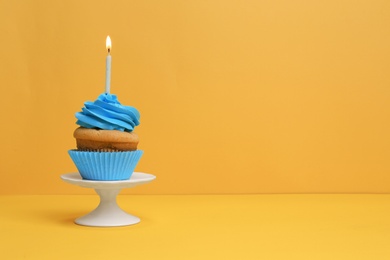 Photo of Birthday cupcake with candle on color background