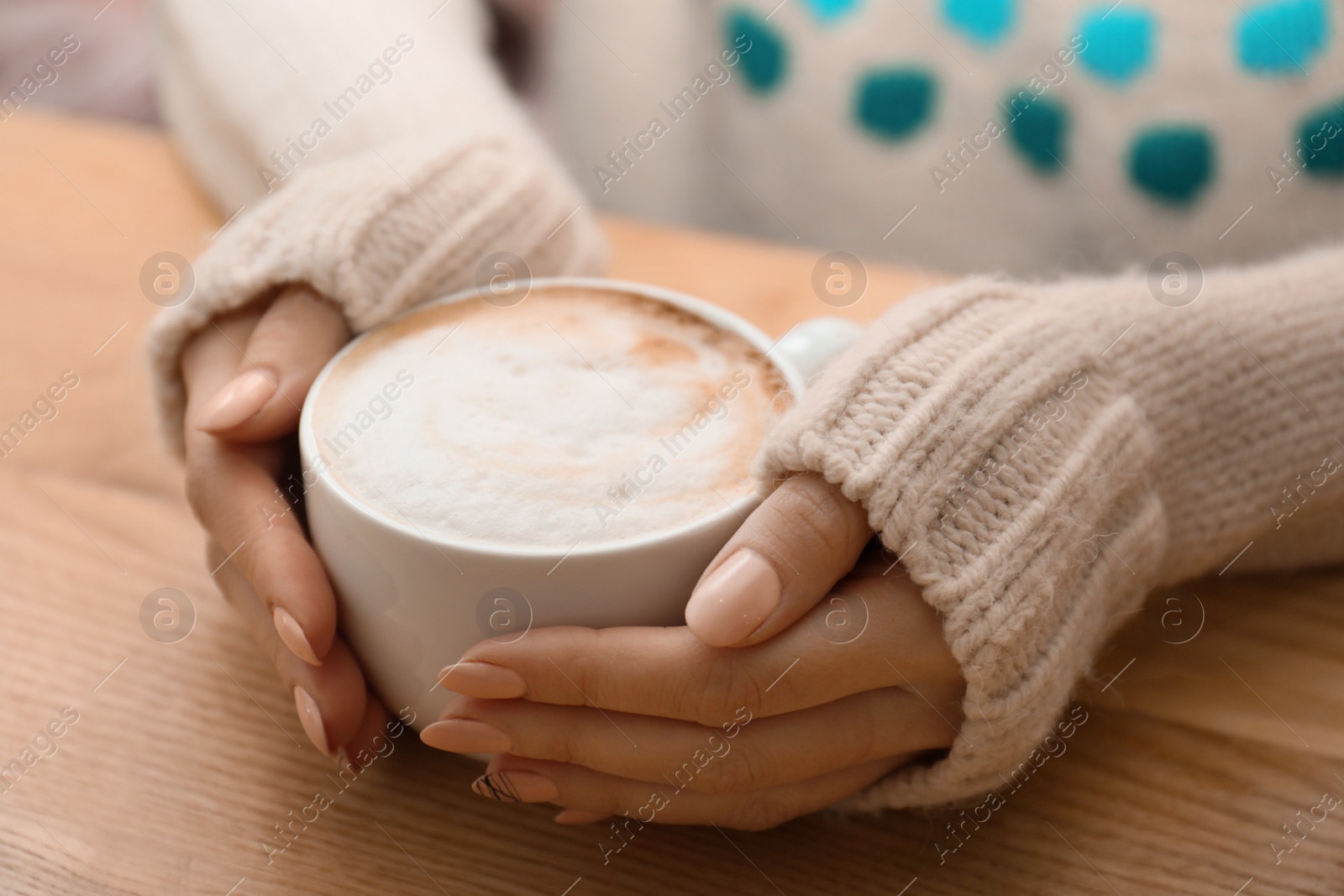 Photo of Woman with cup of aromatic cacao at table, closeup