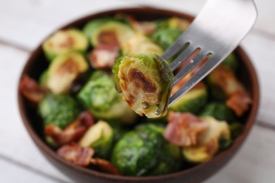 Eating delicious roasted Brussels sprouts at table, closeup. Space for text