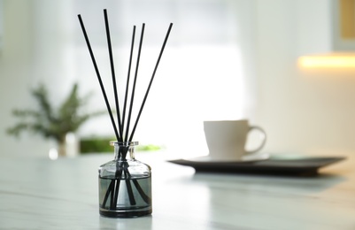 Photo of Aromatic reed air freshener on white table indoors. Space for text