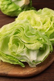 Board with halves of fresh green iceberg lettuce head on wooden table, closeup