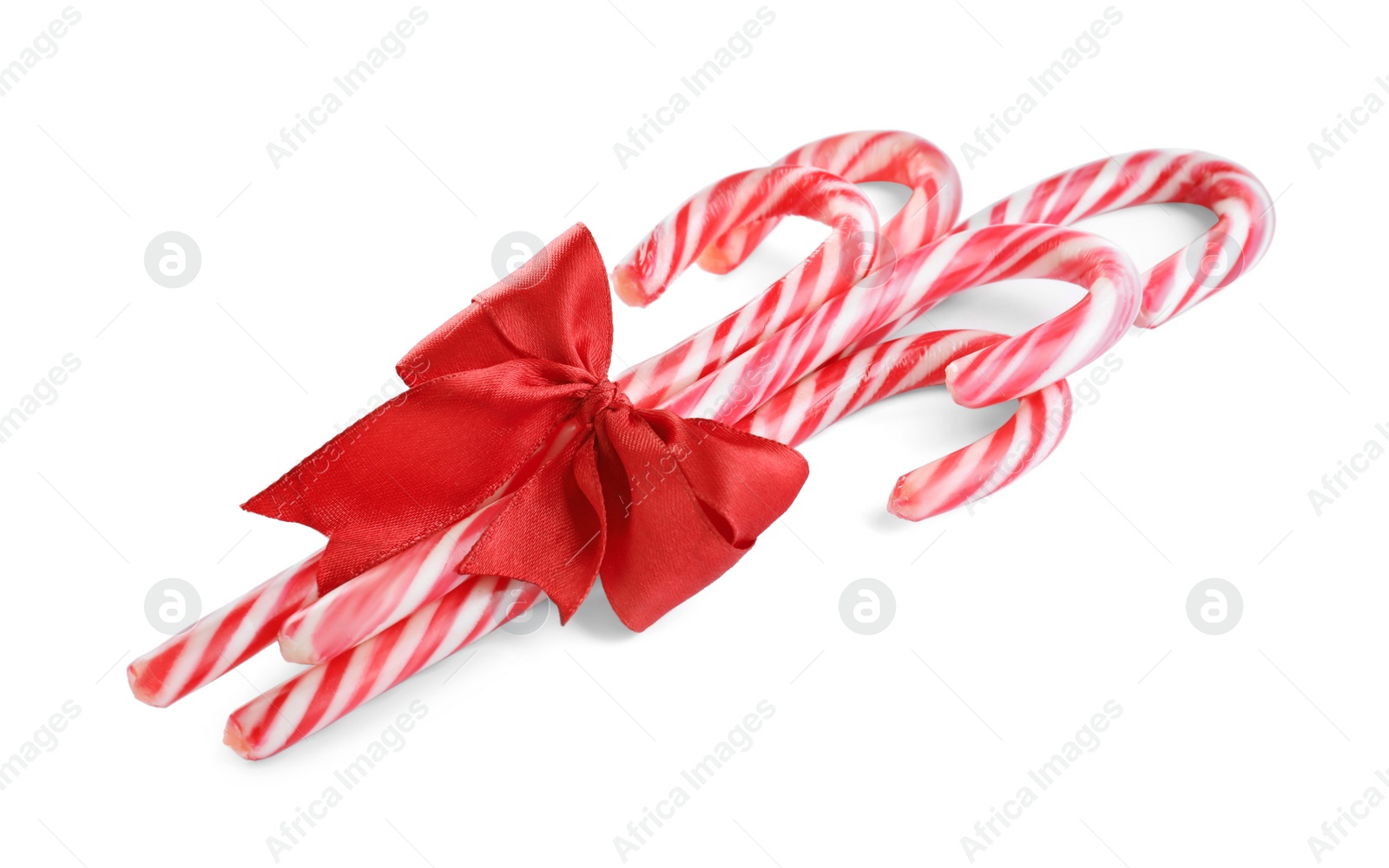 Photo of Sweet Christmas candy canes with red bow on white background