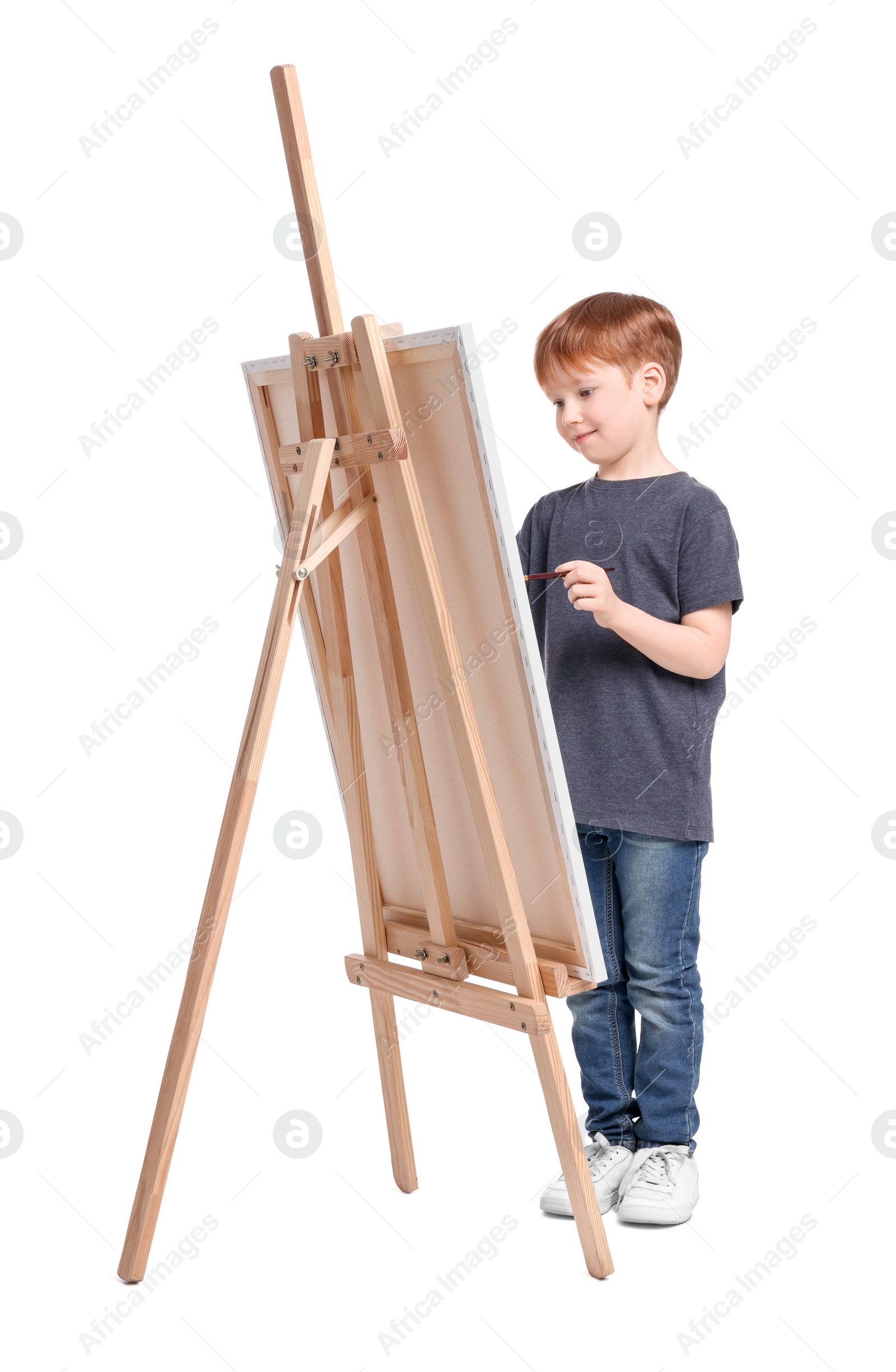 Photo of Little boy painting against white background. Using easel to hold canvas