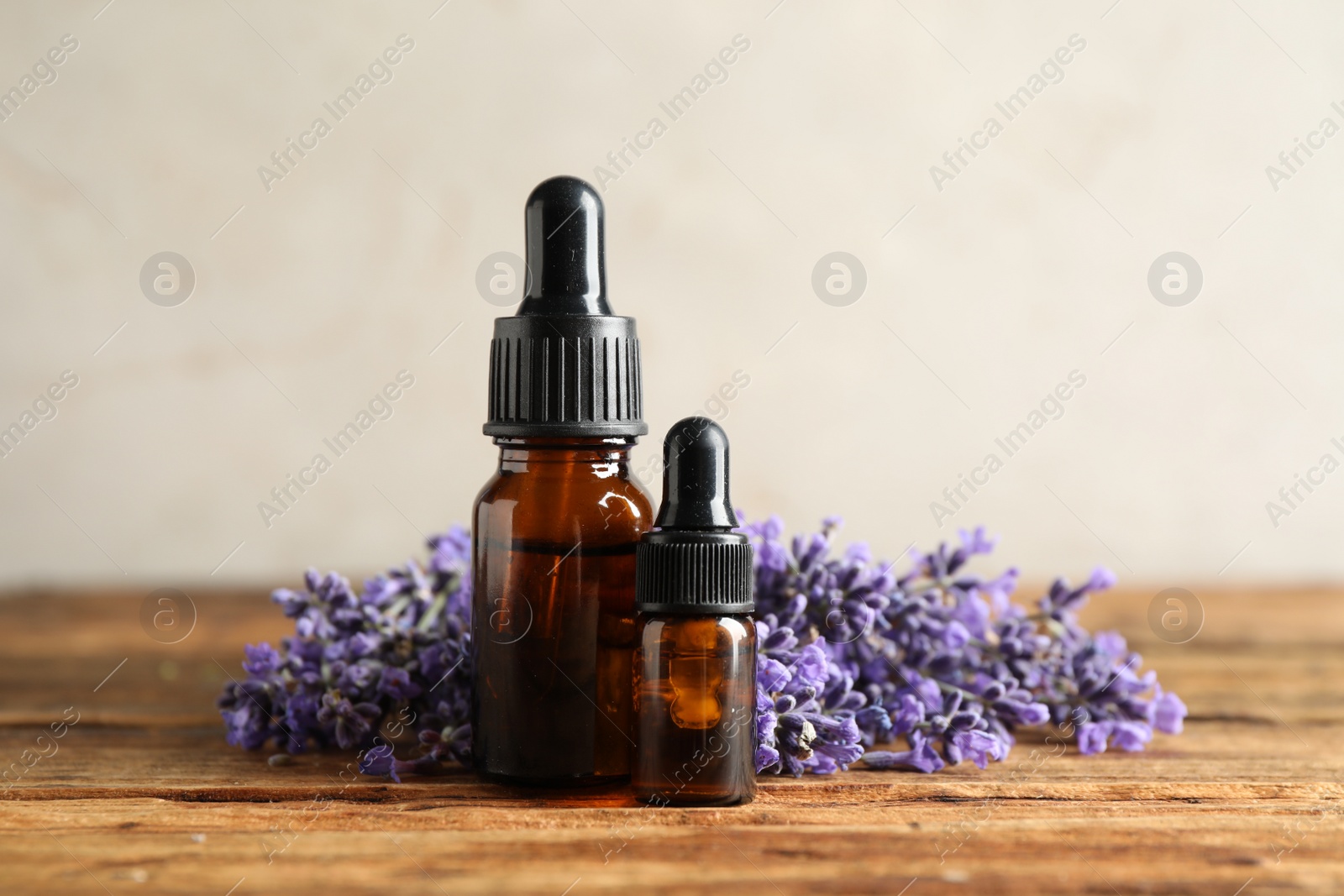 Photo of Bottles of essential oil and lavender flowers on wooden table