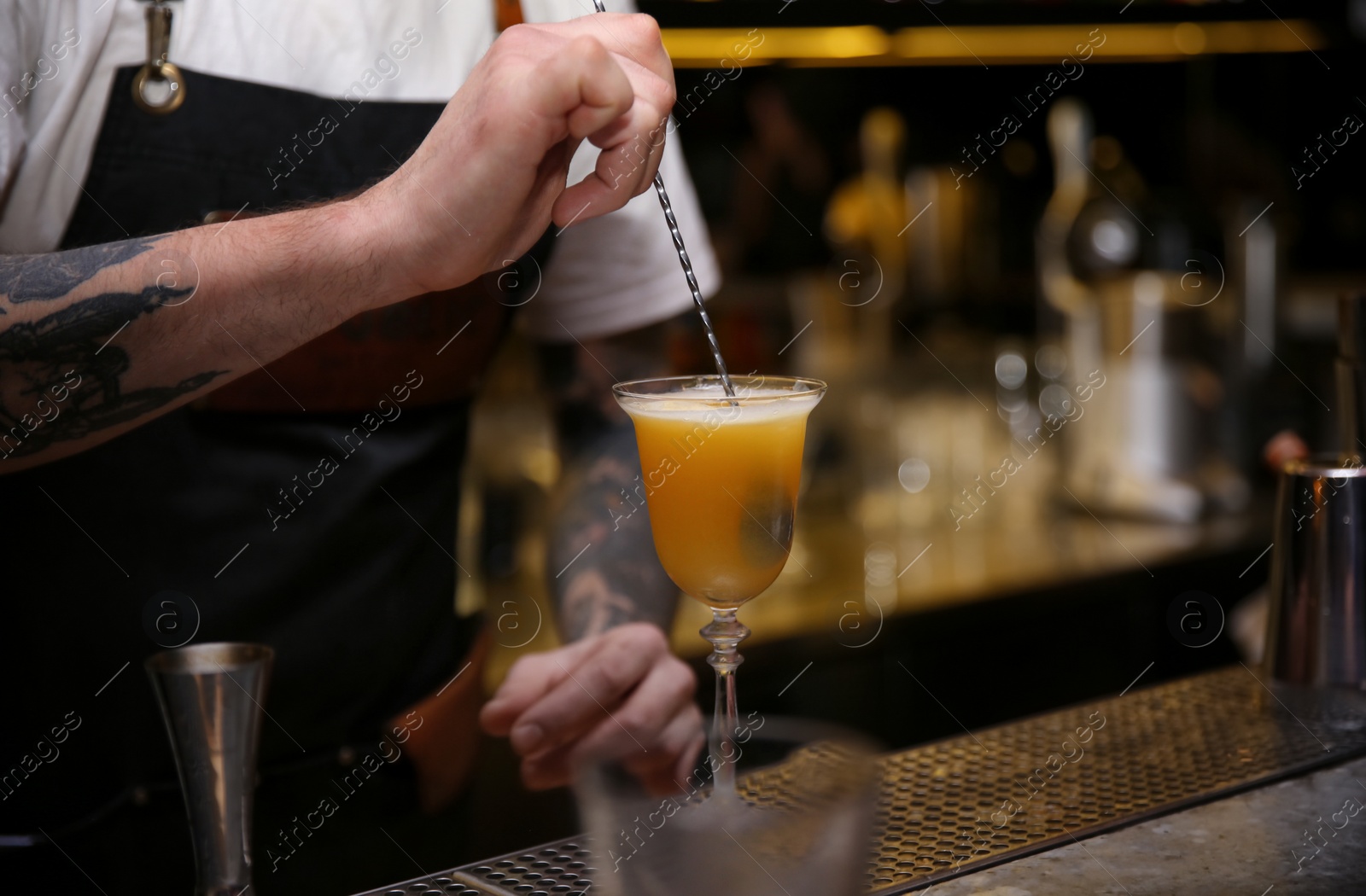 Photo of Bartender preparing tasty cocktail at counter in nightclub, closeup