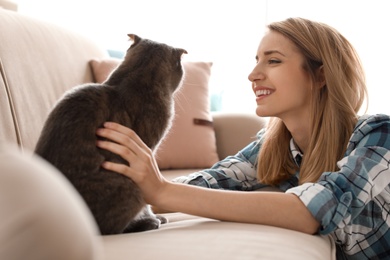 Photo of Young woman with her cute pet cat at home