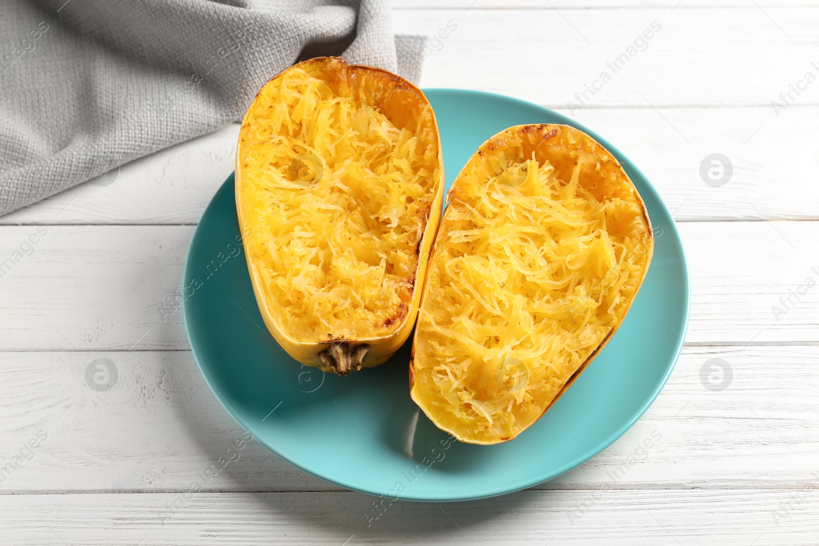 Photo of Plate with cooked spaghetti squash on white wooden background