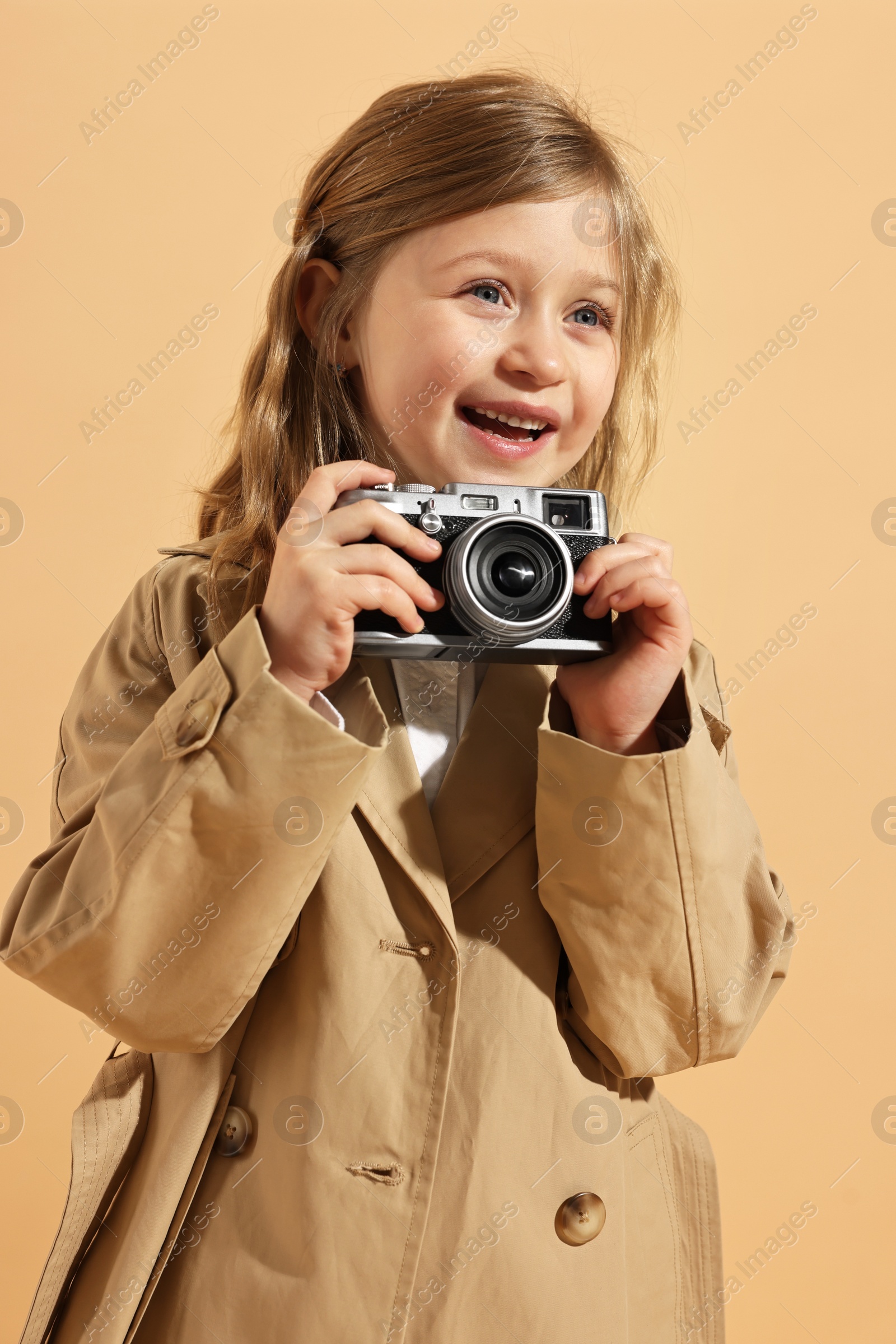 Photo of Fashion concept. Stylish girl with vintage camera on pale orange background