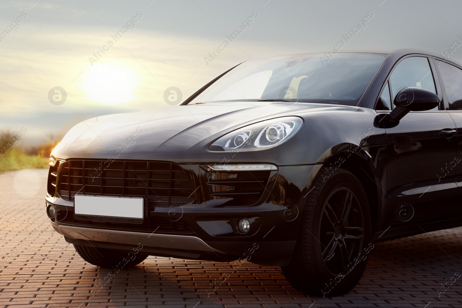 Photo of Modern black car parked on stone pavement outdoors