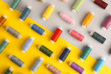 Photo of Different sewing threads on color background, flat lay