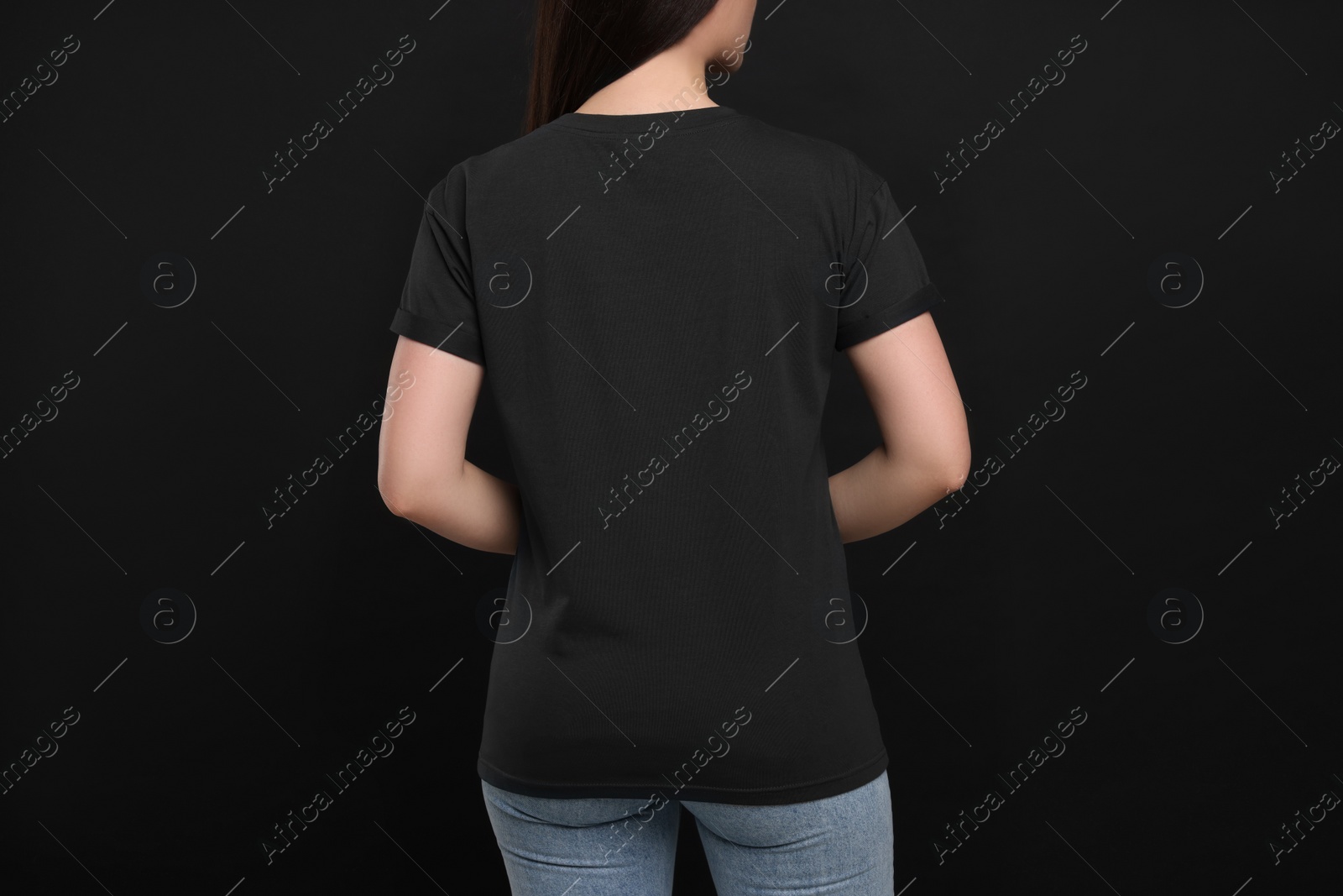 Photo of Woman wearing black t-shirt on dark background, back view