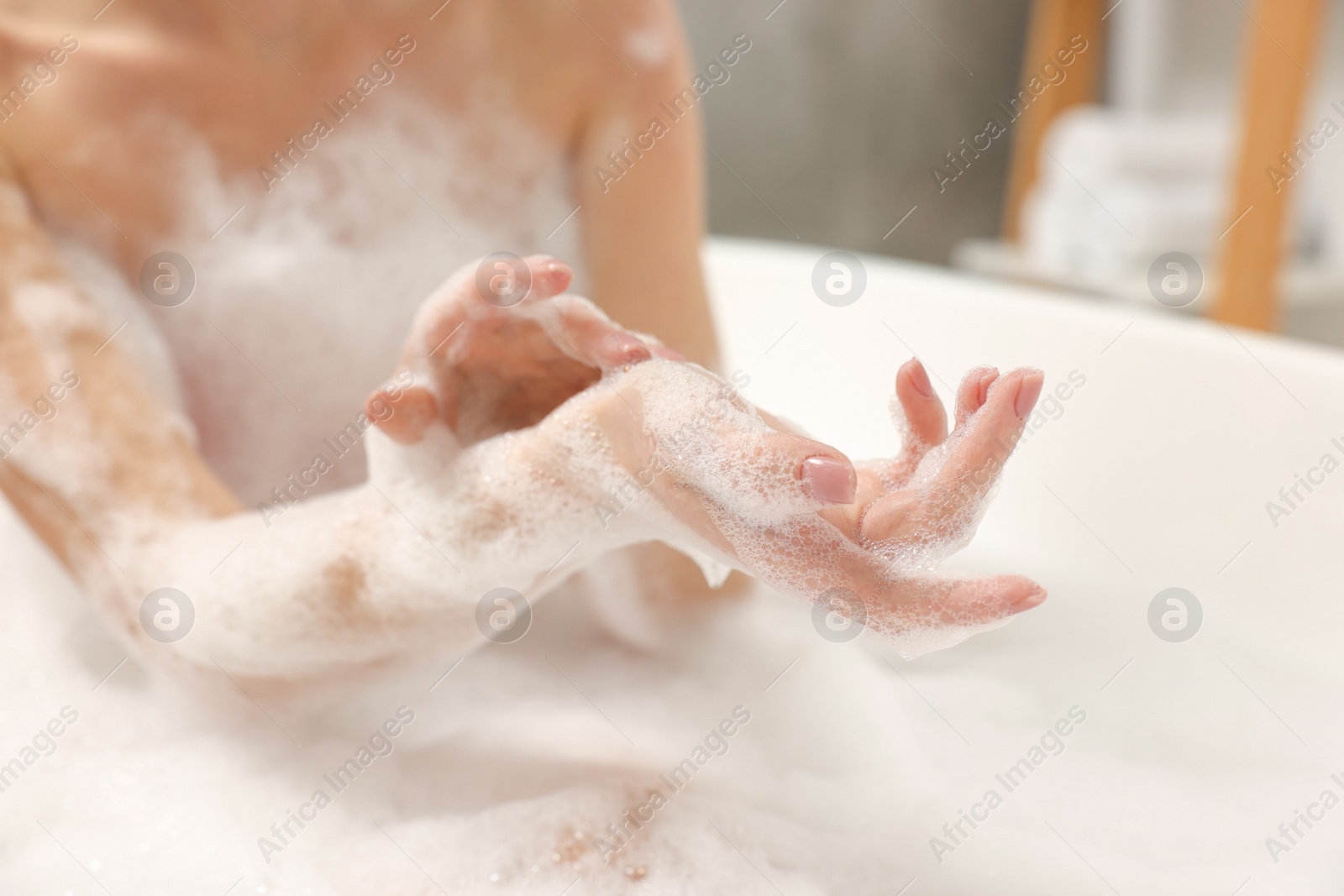 Photo of Woman taking bath with shower gel in bathroom, closeup