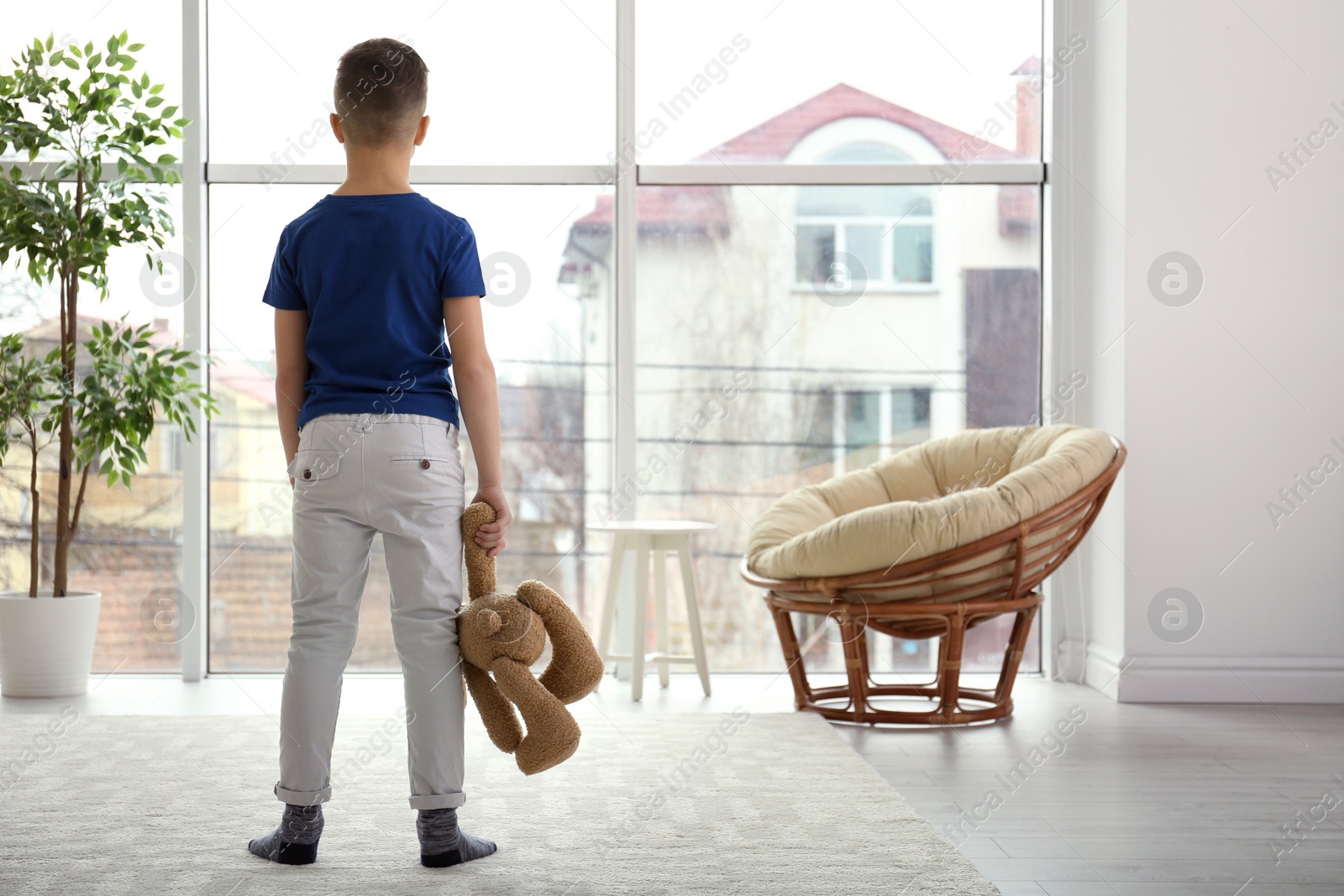 Photo of Lonely little boy with toy bear at home. Autism concept