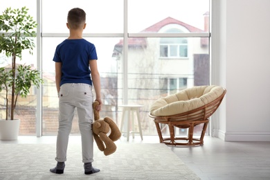 Lonely little boy with toy bear at home. Autism concept