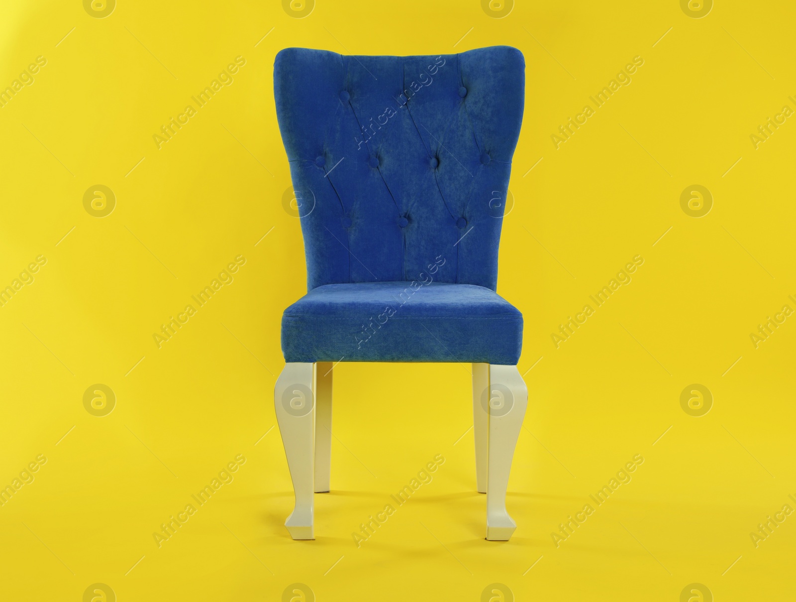 Photo of Stylish blue chair on yellow background. Element of interior design