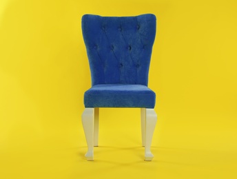 Stylish blue chair on yellow background. Element of interior design