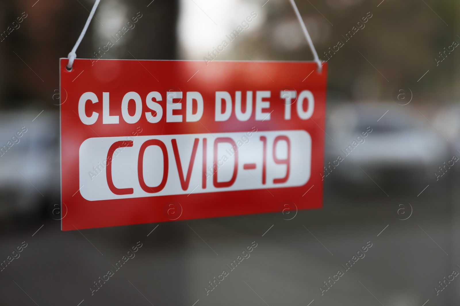 Photo of Red sign with words "Closed Due To Covid-19" hanging on glass door