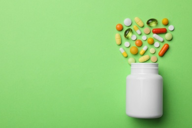 Bottle with different pills on color background, flat lay. Space for text