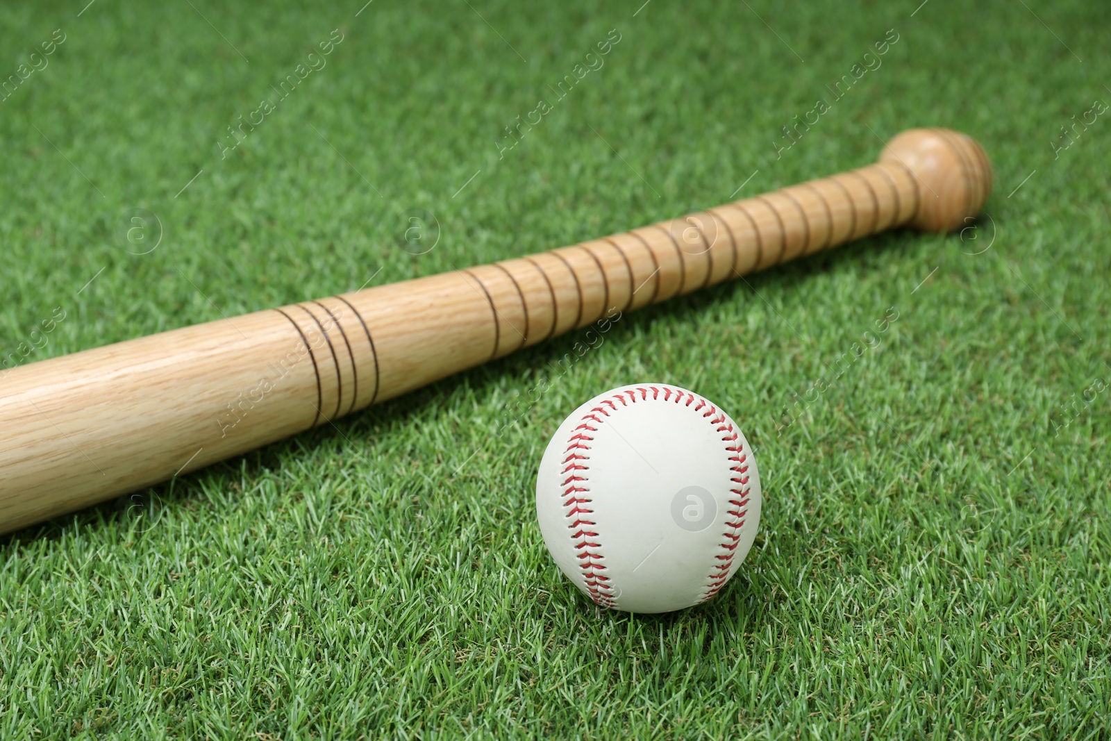 Photo of Wooden baseball bat and ball on green grass. Sports equipment