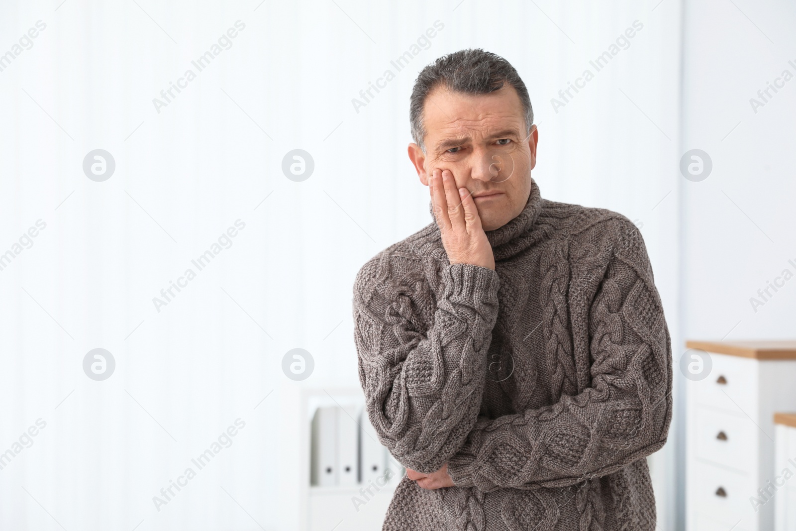 Photo of Mature man suffering from strong tooth pain at home, space for text