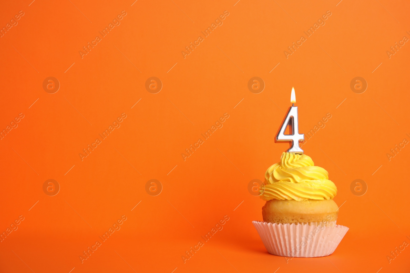 Photo of Birthday cupcake with number four candle on orange background, space for text