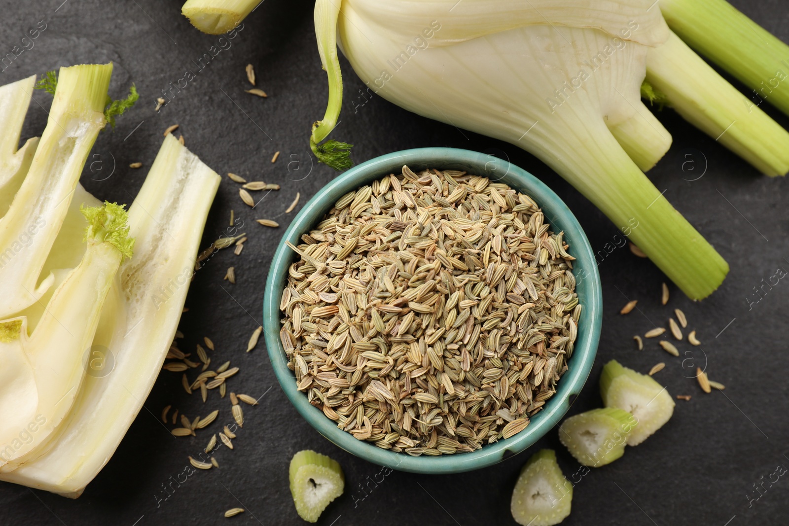 Photo of Fennel seeds in bowl, whole and cut vegetables on gray table, flat lay