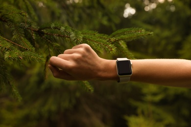 Photo of Woman checking smart watch with blank screen in wilderness, closeup