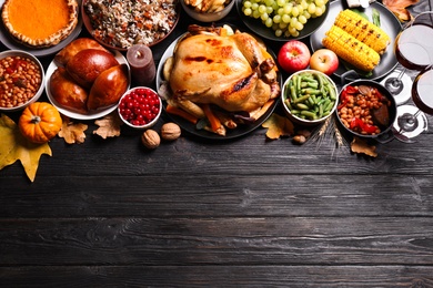 Photo of Traditional Thanksgiving day feast with delicious cooked turkey and other seasonal dishes on black wooden table, flat lay. Space for text