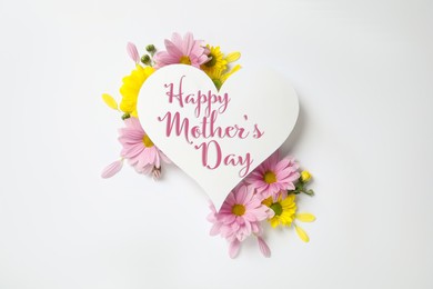 Image of Happy Mother's Day greeting card in shape of heart and beautiful flowers on white background, flat lay