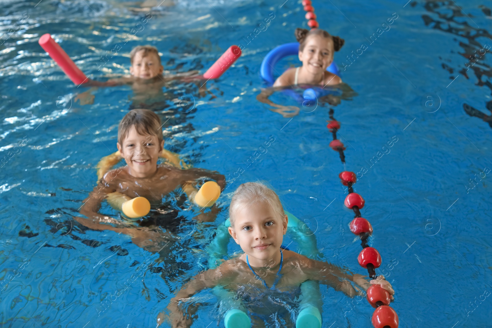 Photo of Little kids with swimming noodles in indoor pool