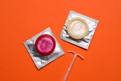 Photo of Contraception choice. Condoms and intrauterine device on terracotta background, flat lay