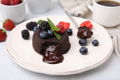 Photo of Plate with delicious chocolate fondant, berries and mint on white table, closeup