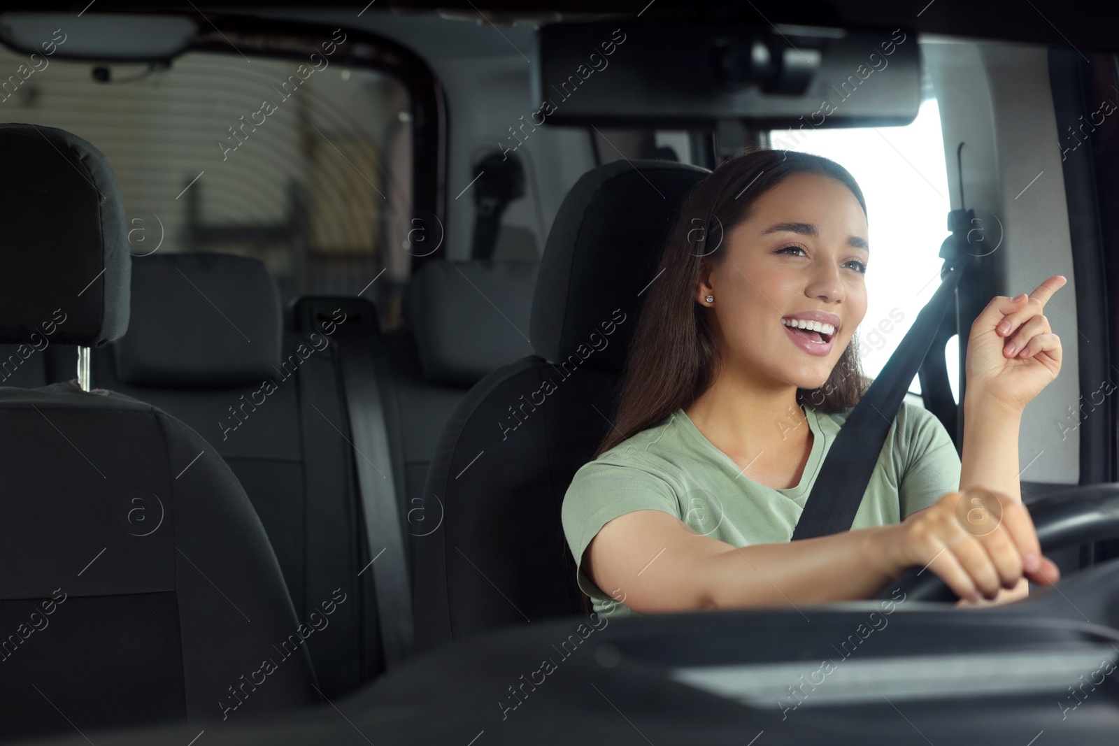 Photo of Listening to radio. Beautiful woman enjoying music in car, view through windshield