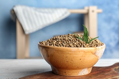Photo of Bowl of hemp seeds on table against color background