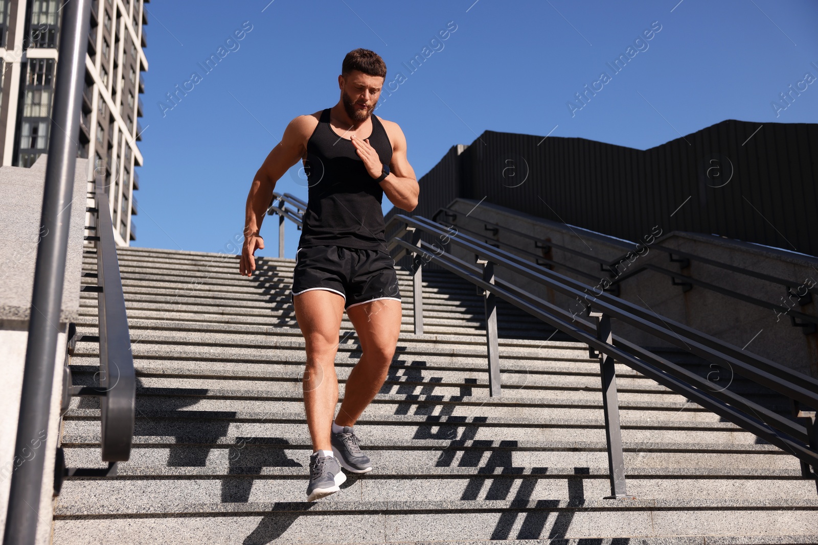 Photo of Man running down stairs outdoors on sunny day, low angle view