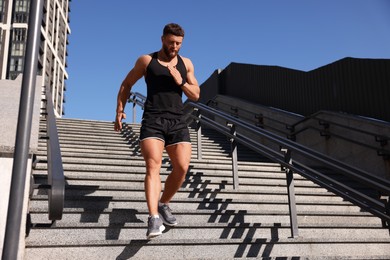 Man running down stairs outdoors on sunny day, low angle view