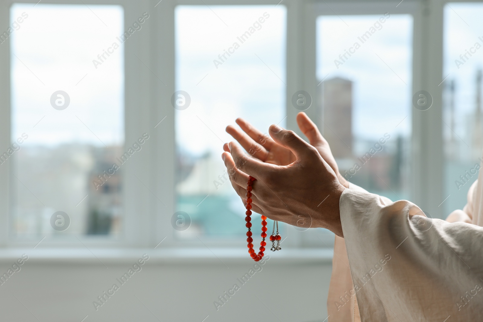 Photo of Muslim man with misbaha praying indoors, closeup. Space for text