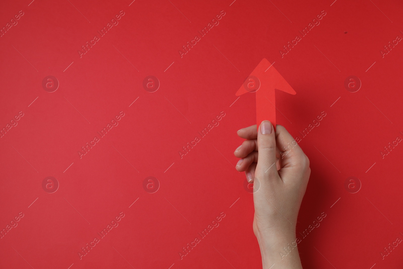 Photo of Woman holding paper arrow on red background, top view. Space for text