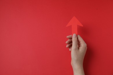 Photo of Woman holding paper arrow on red background, top view. Space for text