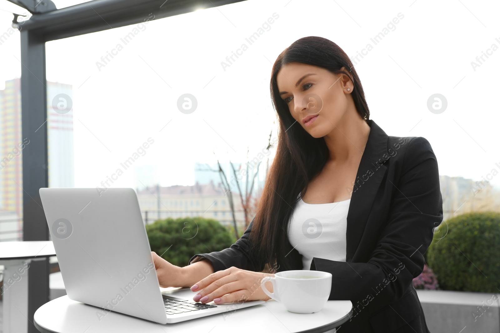 Photo of Businesswoman working with laptop in outdoor cafe. Corporate blog