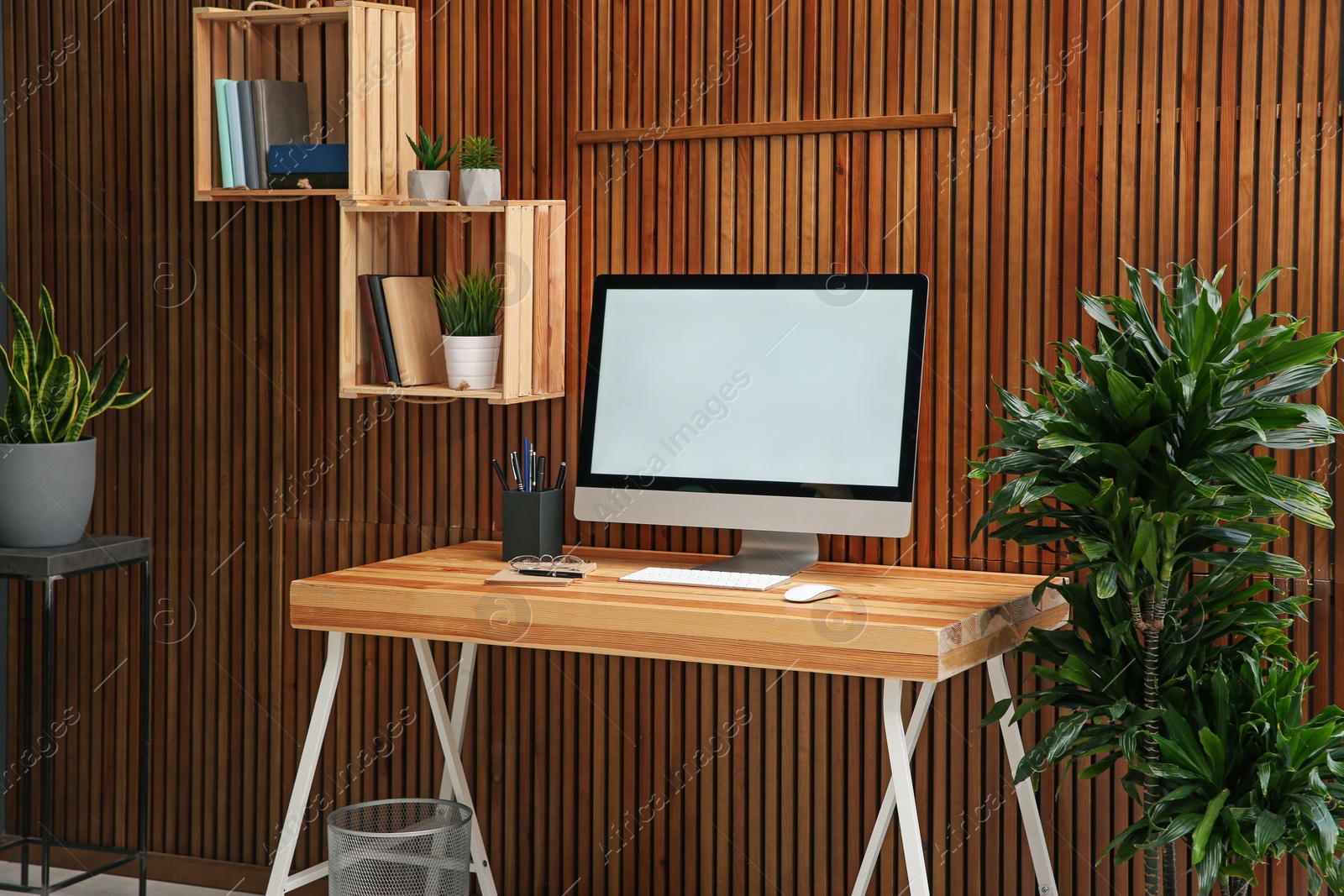 Photo of Comfortable workplace with computer near wooden wall in stylish room interior. Home office design