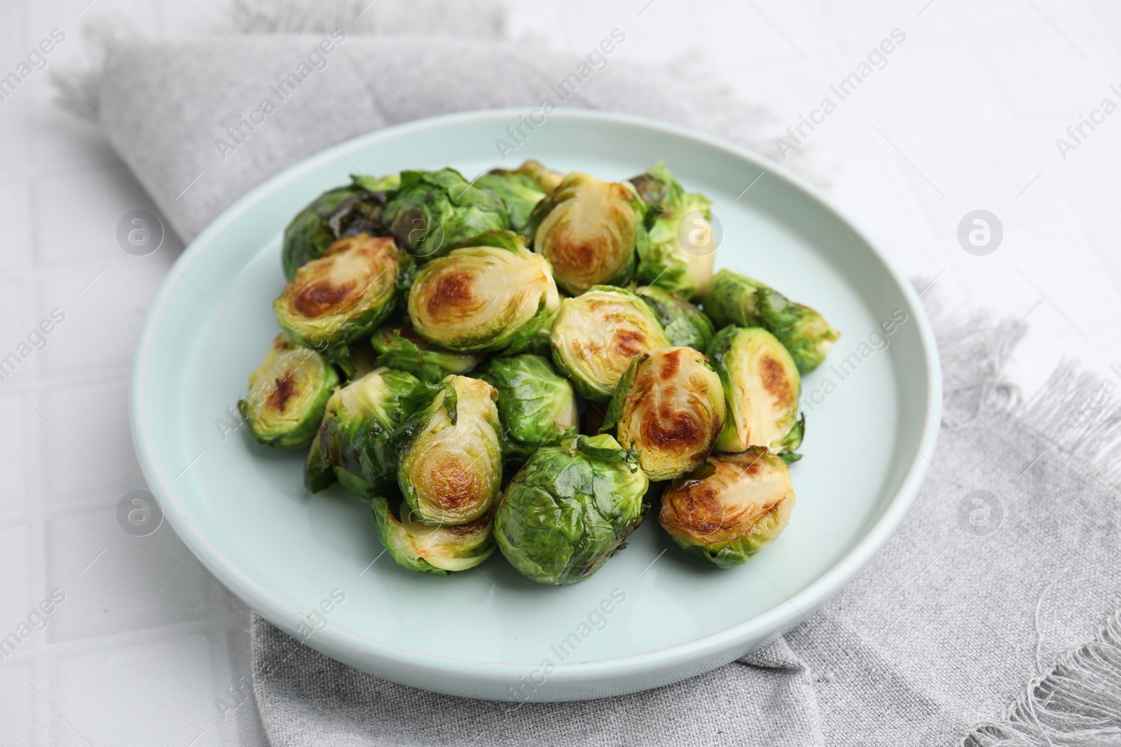 Photo of Delicious roasted Brussels sprouts on white tiled table