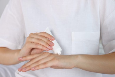 Photo of Woman applying cream on her hand indoors, closeup