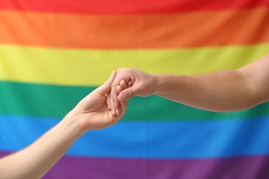Photo of Gay couple holding hands on rainbow background