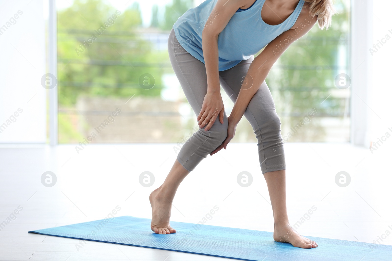 Photo of Woman in sportswear suffering from knee pain at gym, closeup