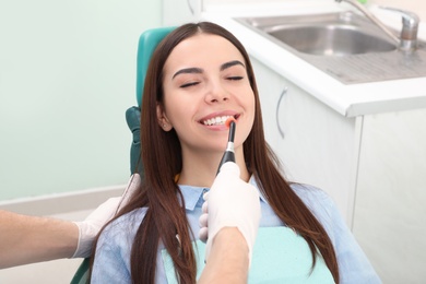 Photo of Professional dentist working with patient in modern clinic. Teeth whitening